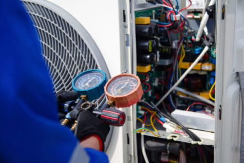 Air conditioner service .The air conditioner technician is using a gauge to measure the refrigerant pressure. air compressor.